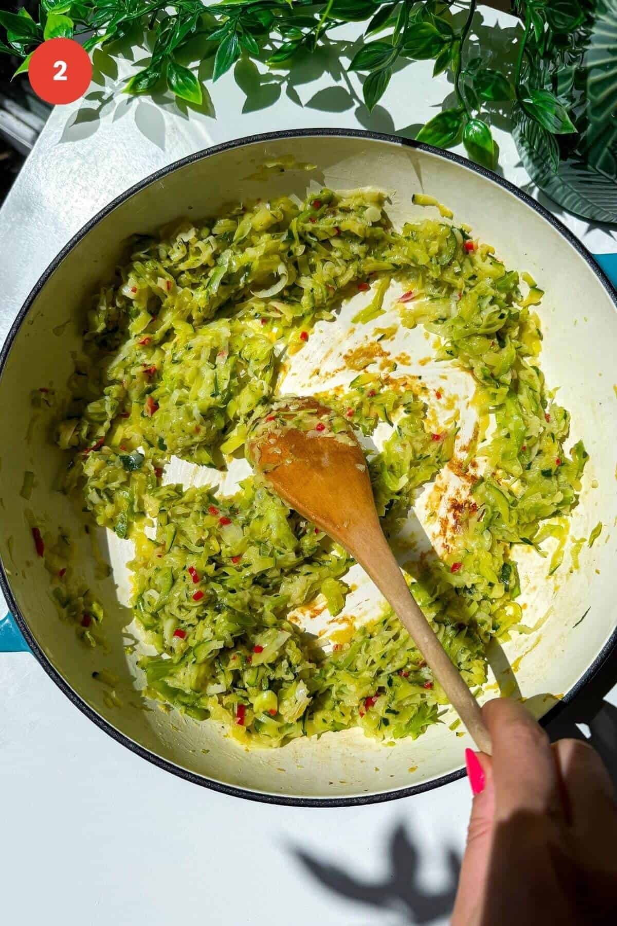 Wooden spoon stirring cooked zucchini, leeks and chili.