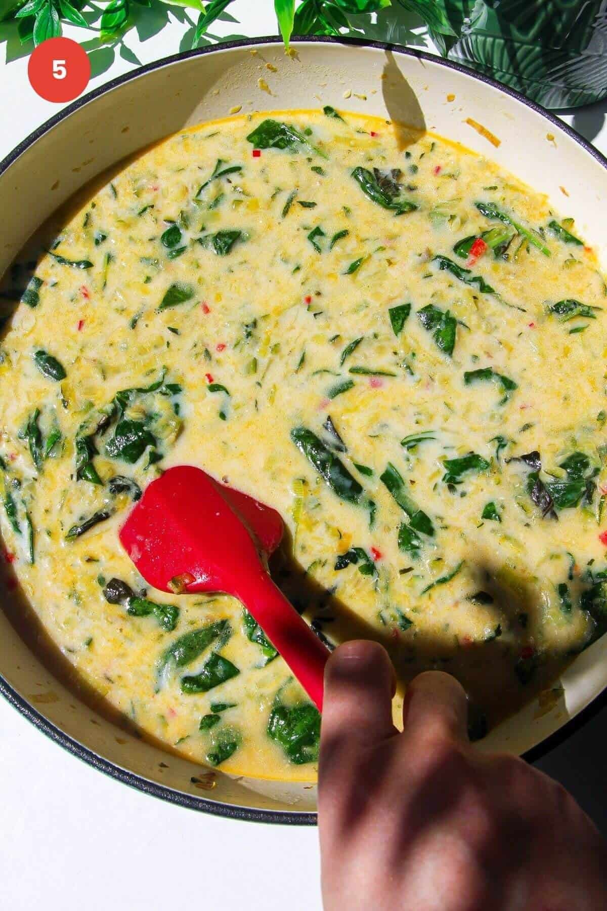 Mixing stock and milk through greens in a large skillet.
