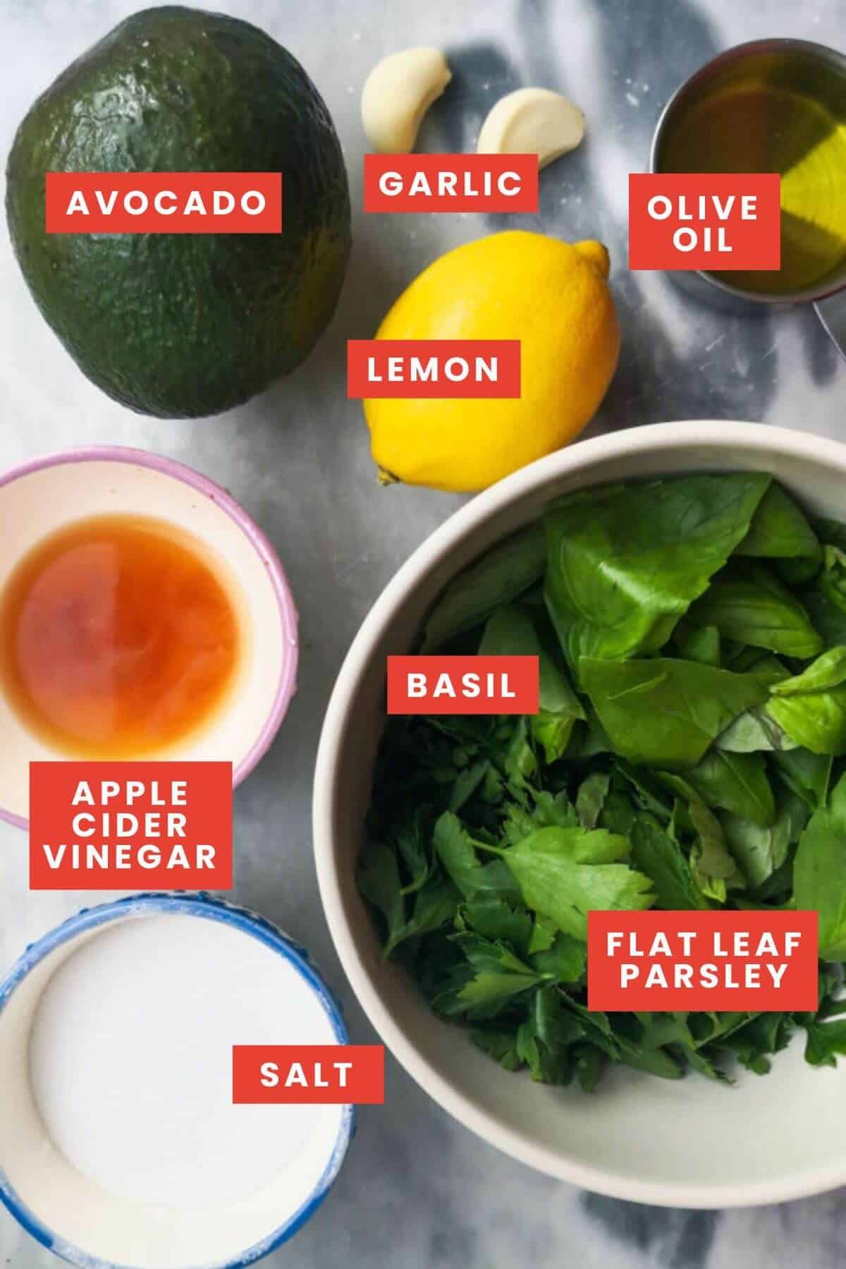 Ingredients for green goddess salad dressing laid out on a grey marble background and labelled.