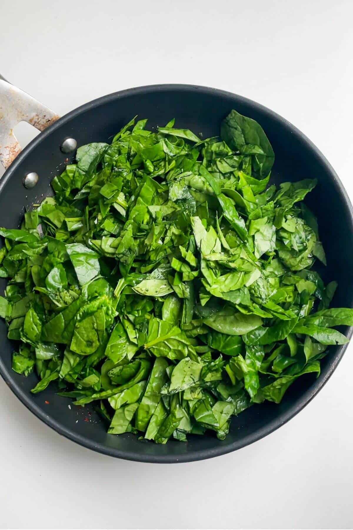 Spinach leaves in a small black pan.
