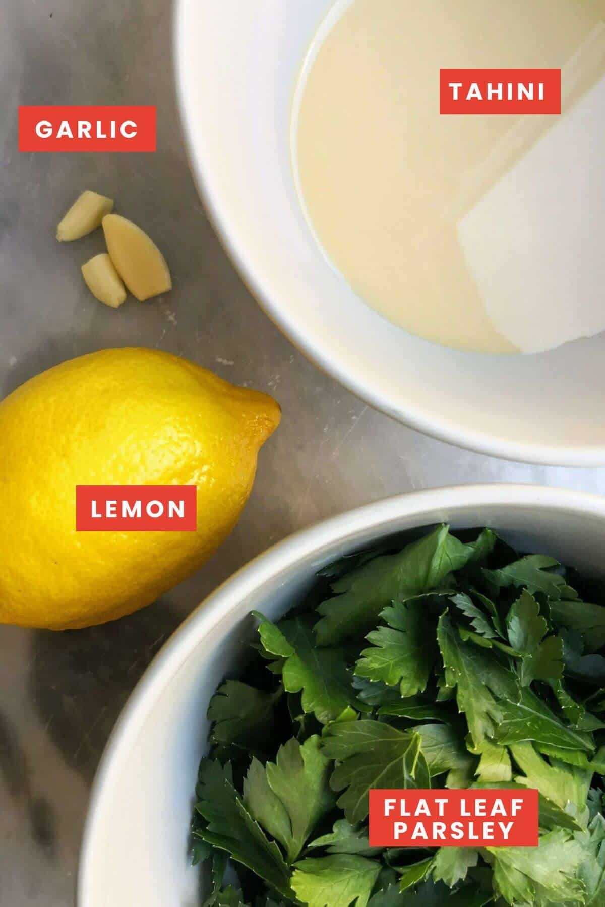 Ingredients for green tahini sauce laid out on a grey marble background.