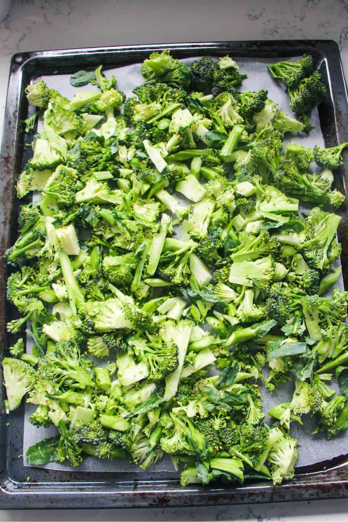 Chopped broccoli laid out on an oven tray.