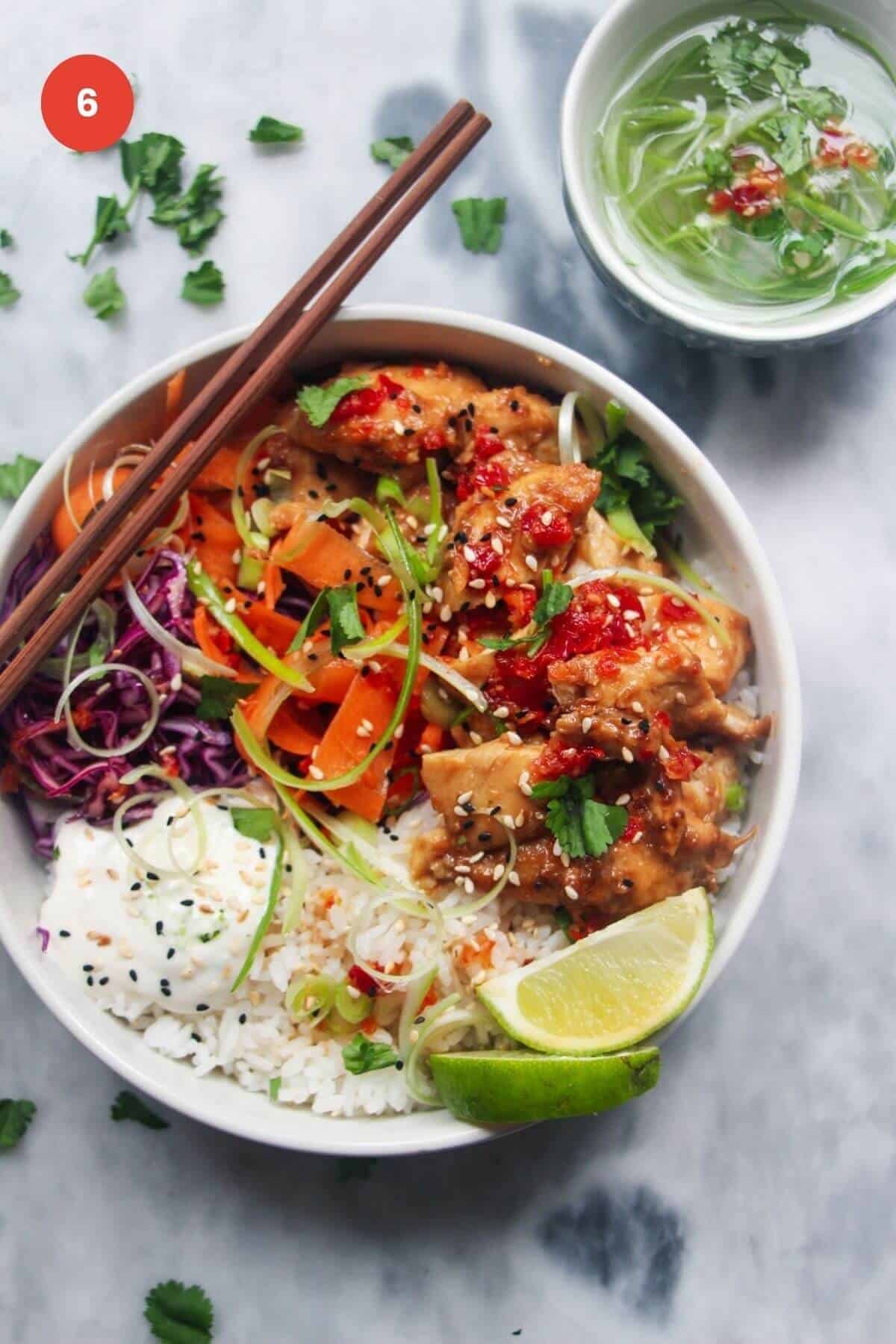 Chicken poke bowl with chopsticks and lime wedge on the side.