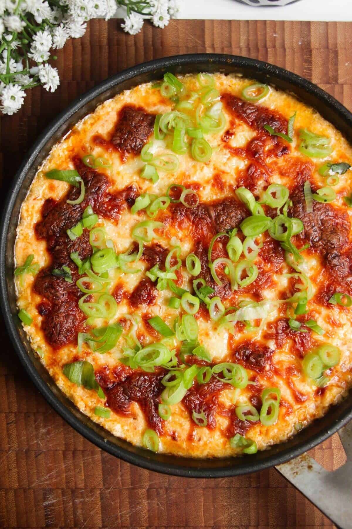 Buffalo chicken dip baked and topped with scallions.
