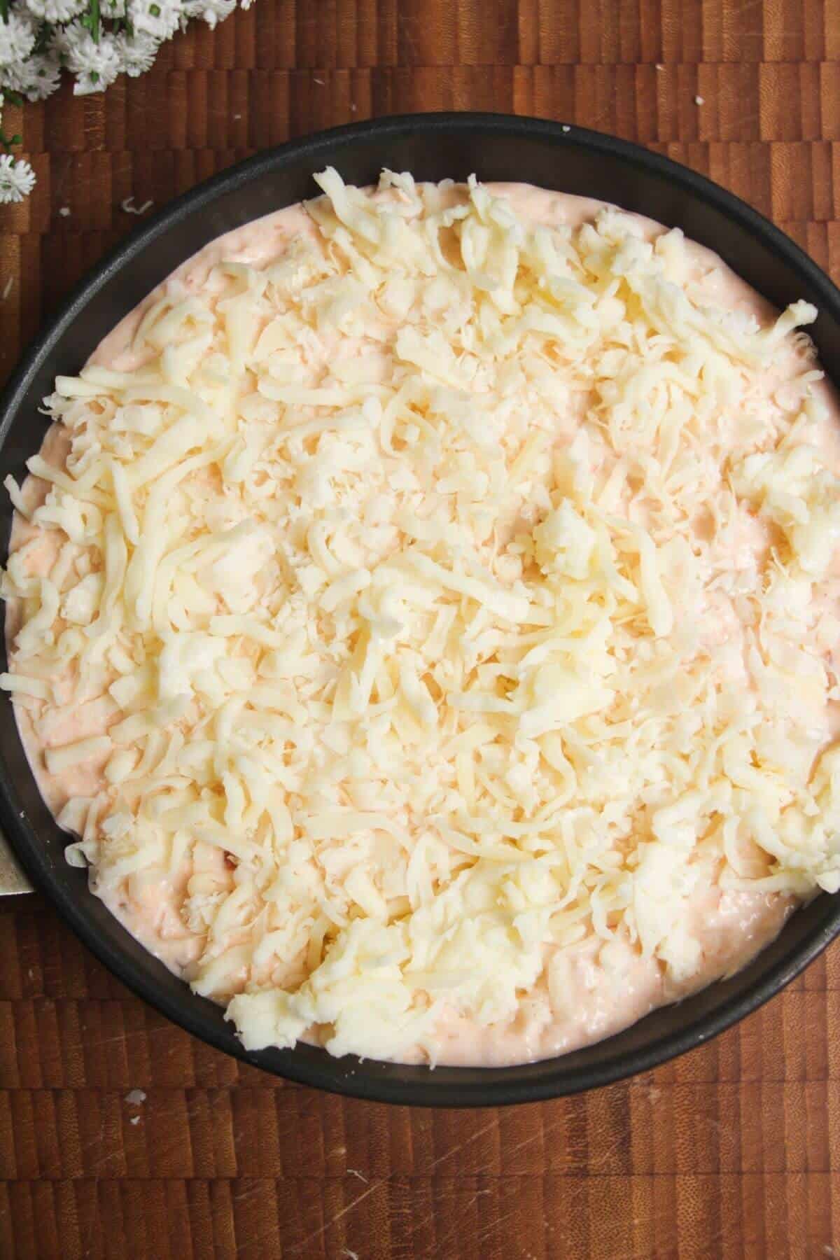 Buffalo chicken dip topped with cheese in a small pan.