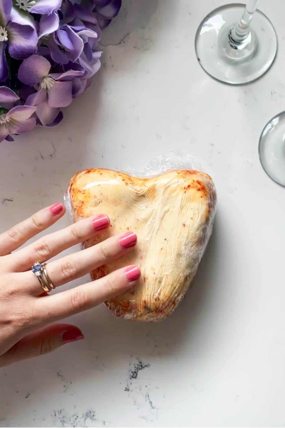Heart shaped cheese wrapped in cling film.