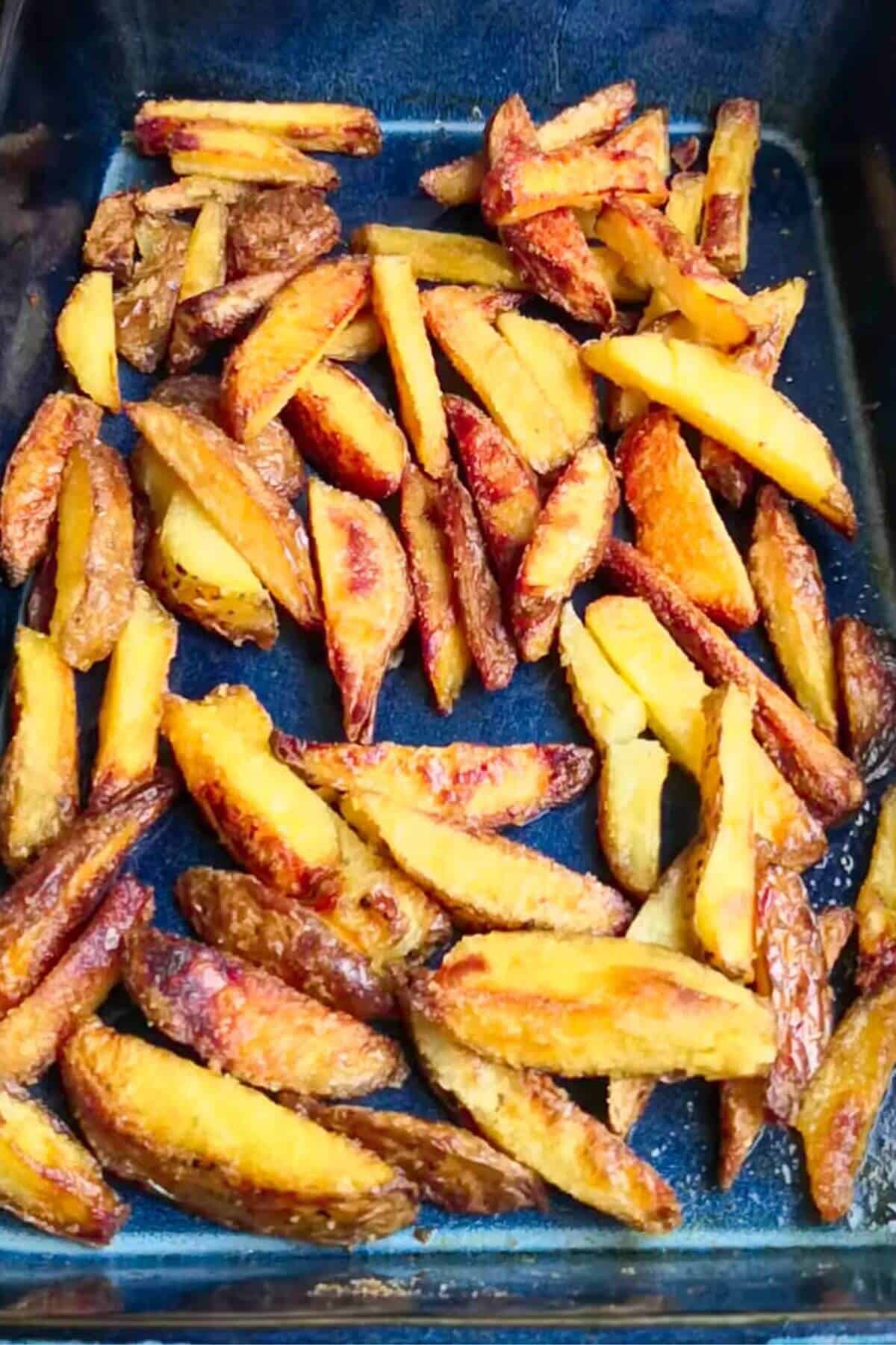 Homemade oven chips in a large blue roasting dish.