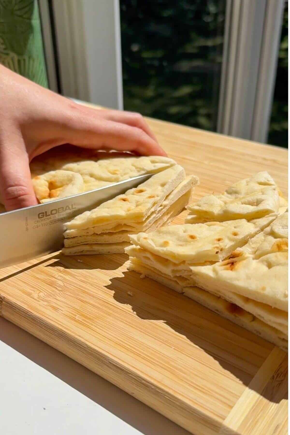 Chopping pita bread into triangles.