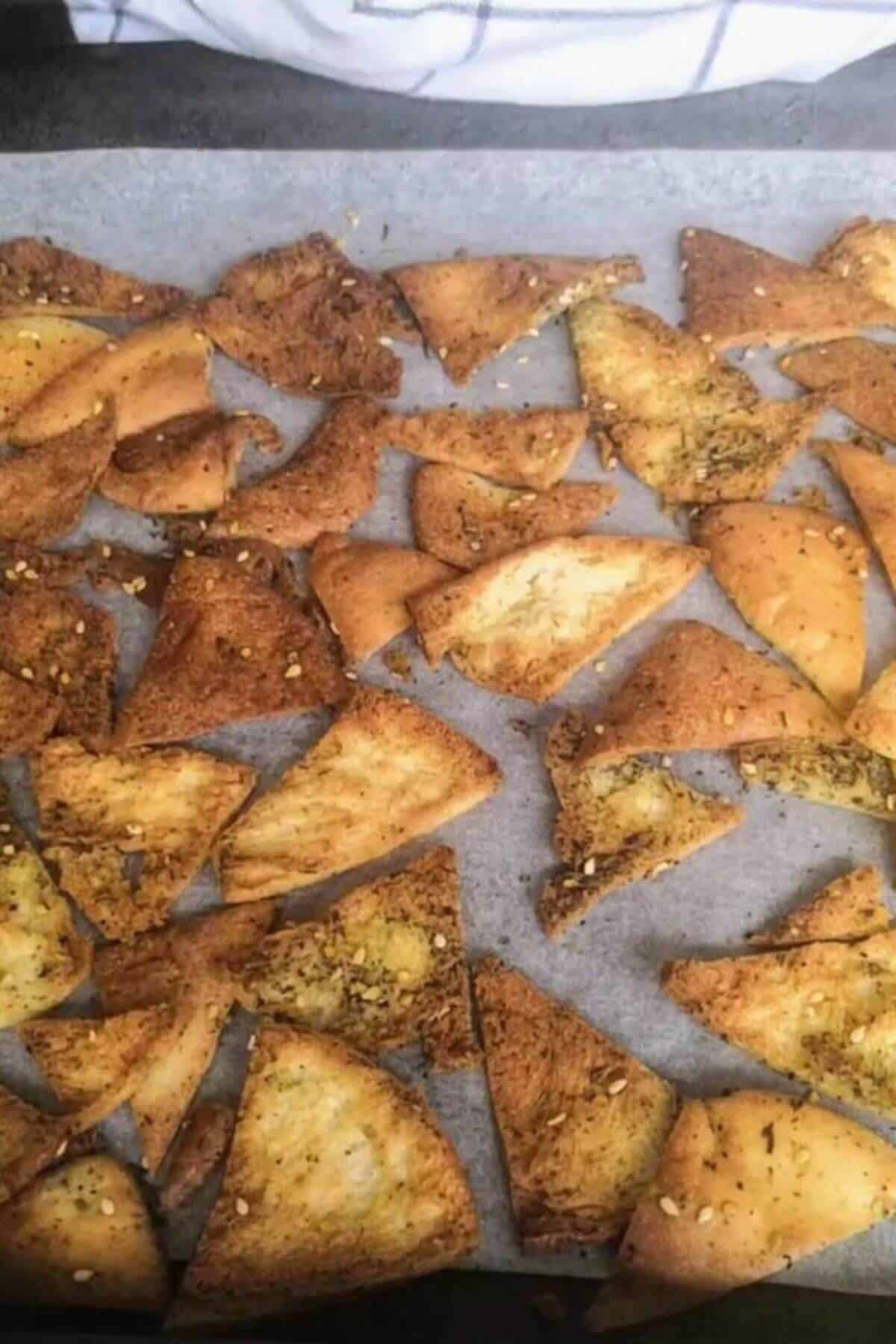 Cooked pita chips on a baking paper lined tray