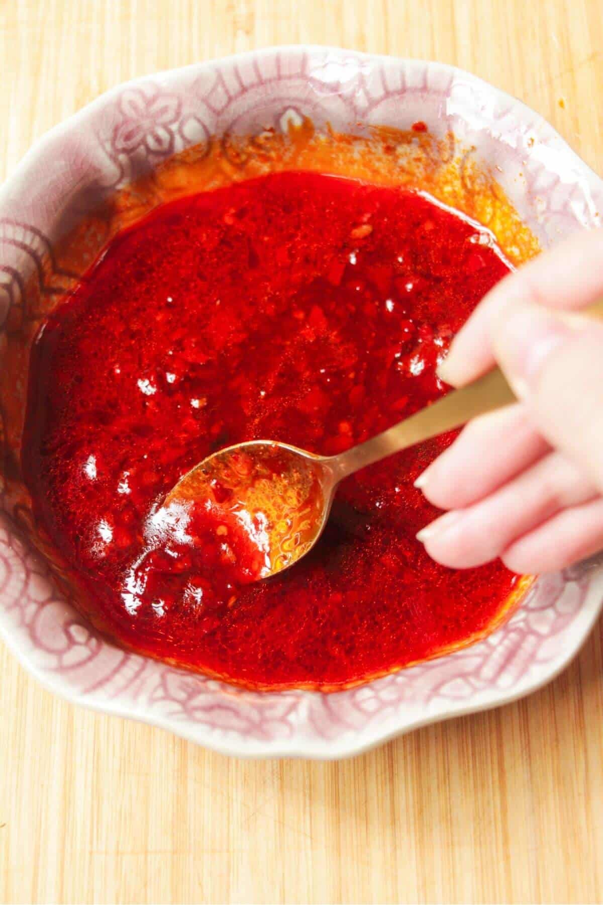 Mixing honey harissa sauce in a small pink bowl.