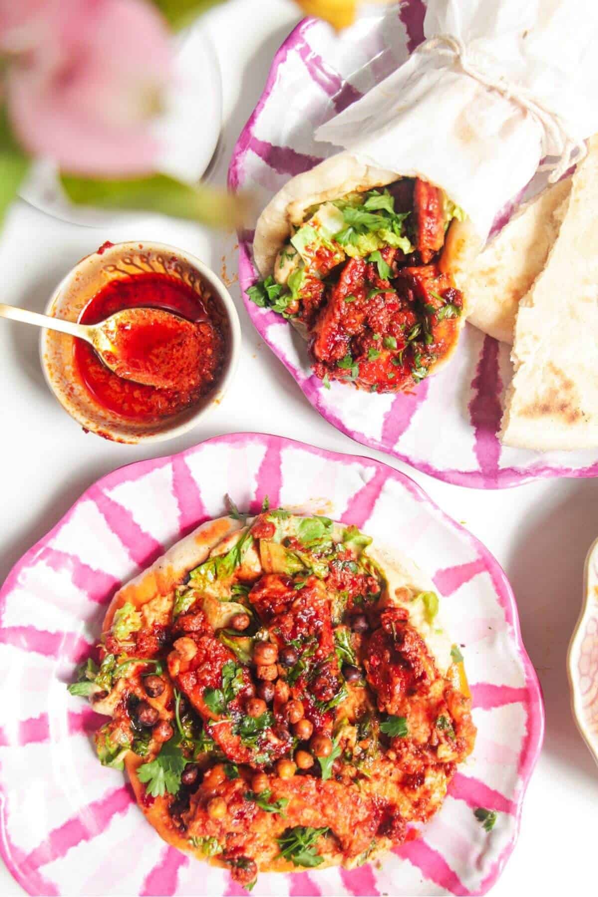Two flatbreads with honey harissa halloumi, hummus and chickpeas on top.