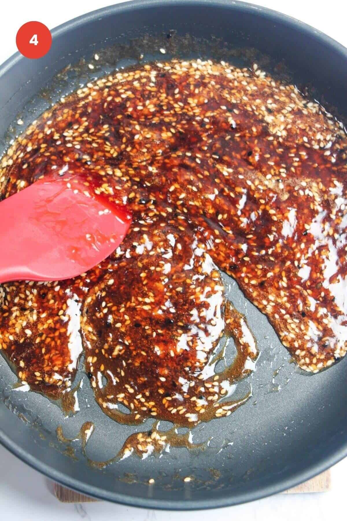 Spatula stirring honey sesame sauce in pan.