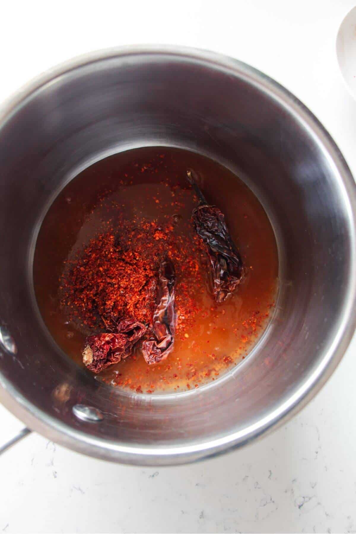 Honey and chilli flakes in a small silver pot.