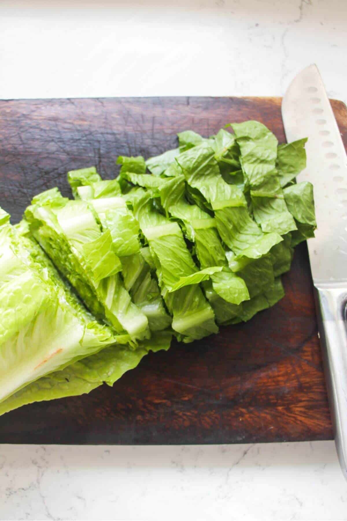 Romaine lettuce sliced on a dark wooden board.