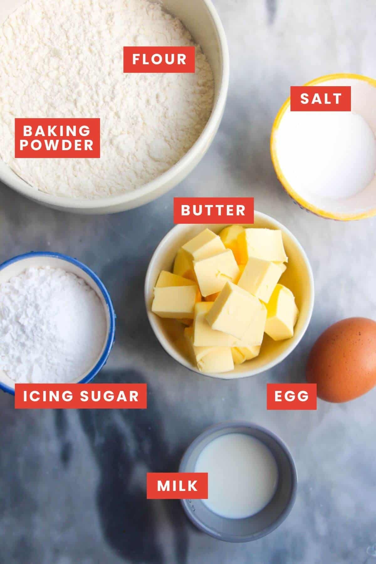 Ingredients for pastry laid out on a grey marble background and labelled.