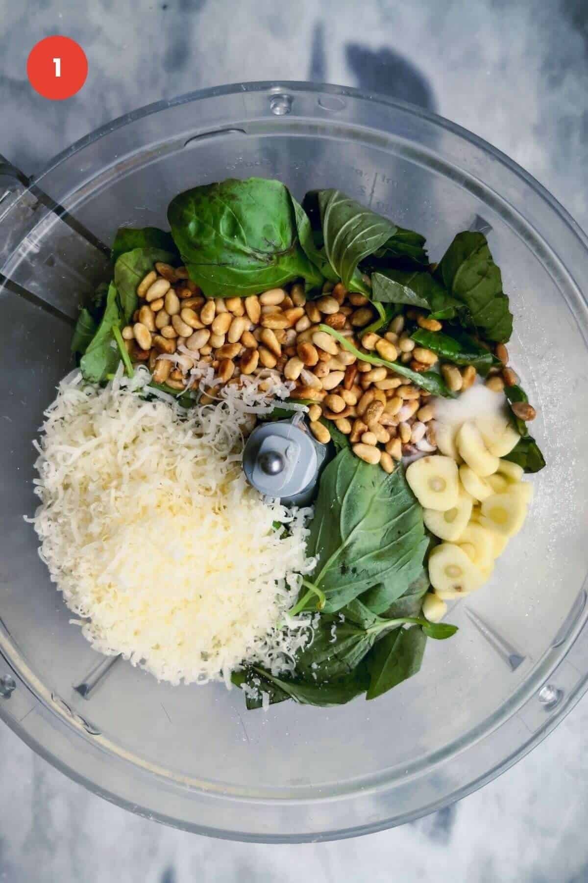 Ingredients for basil pesto in the bowl of a food processor.