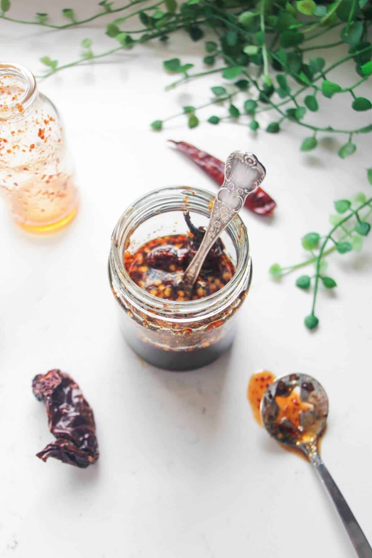 Hot honey sauce in a glass jar with silver spoon inside.