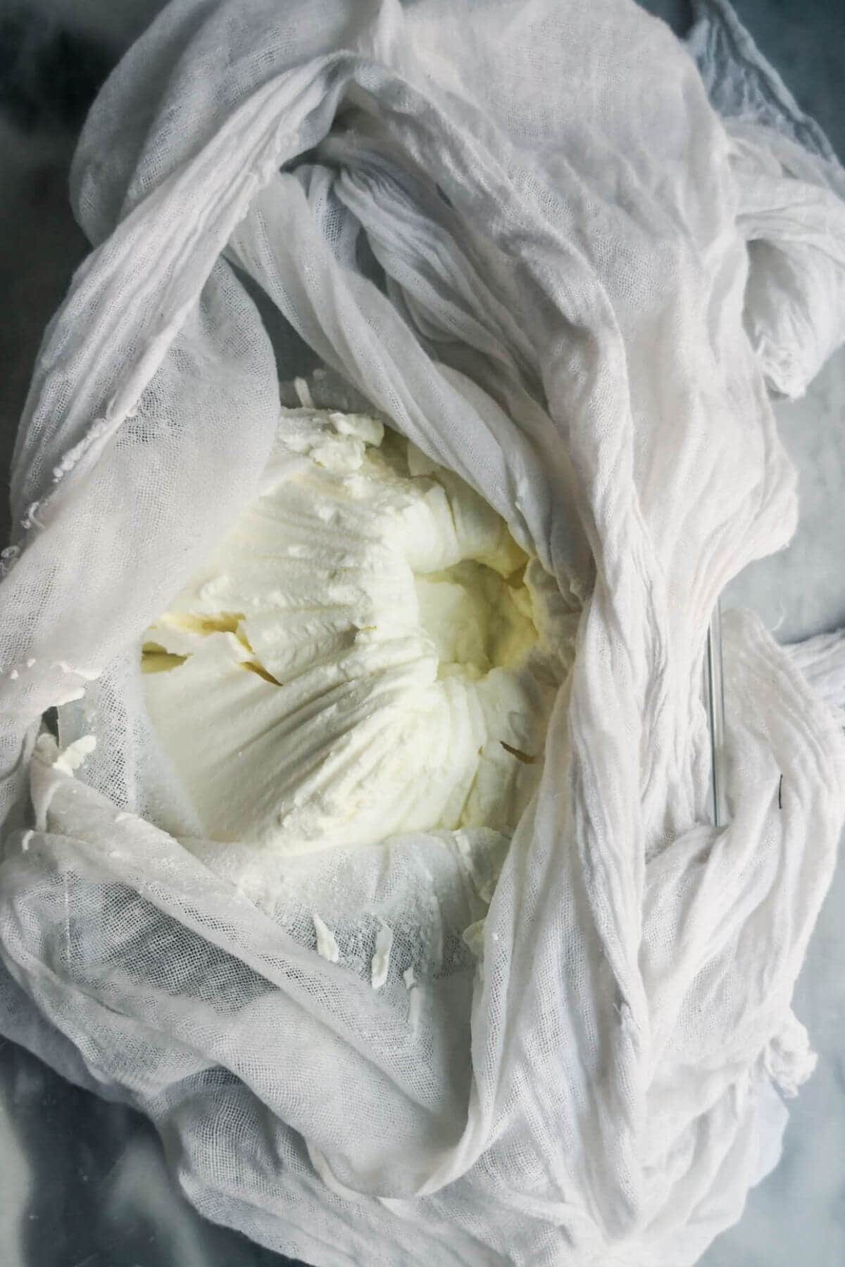 Strained labneh in a white cheesecloth.