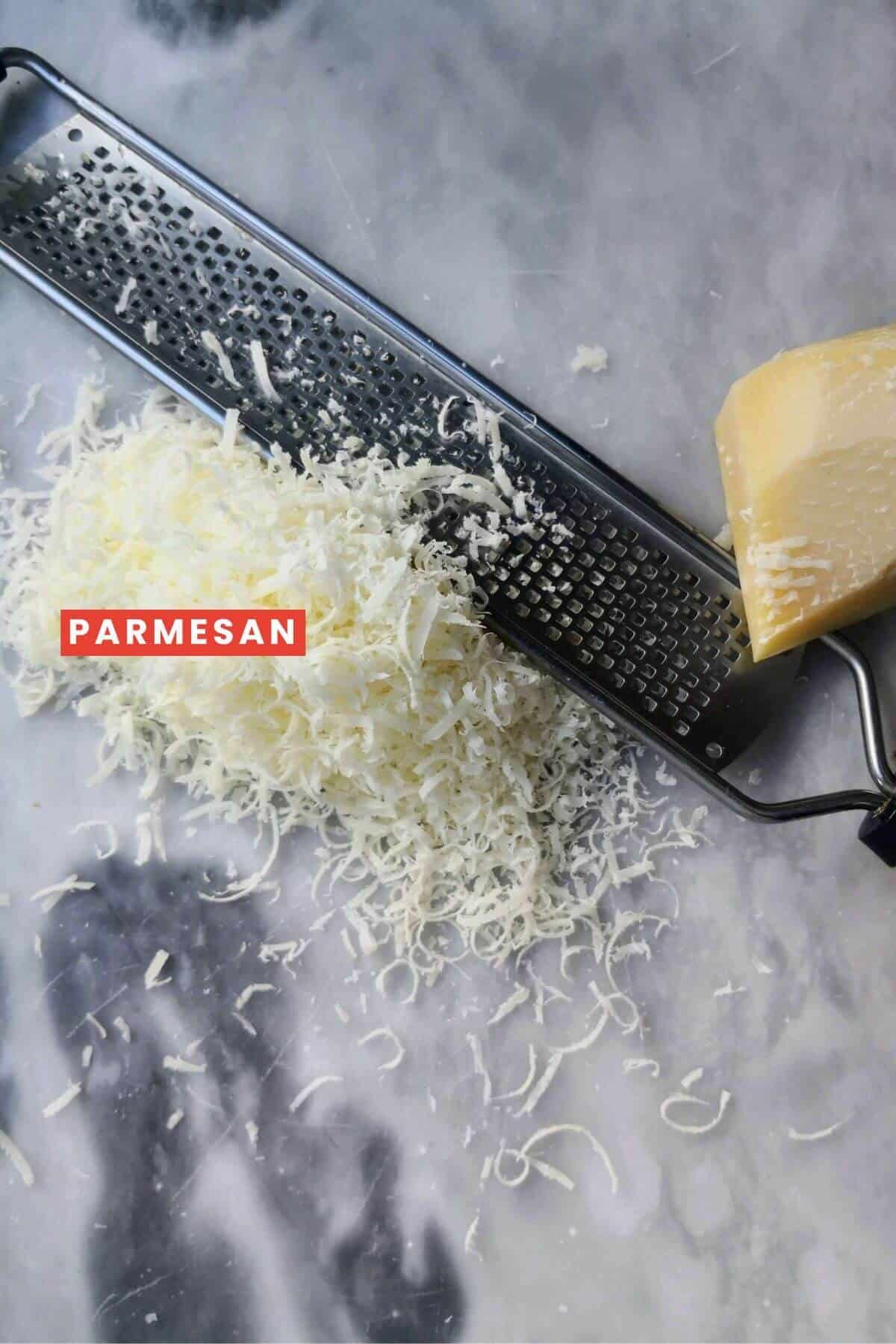Grated parmesan cheese and a grater on a kitchen surface.