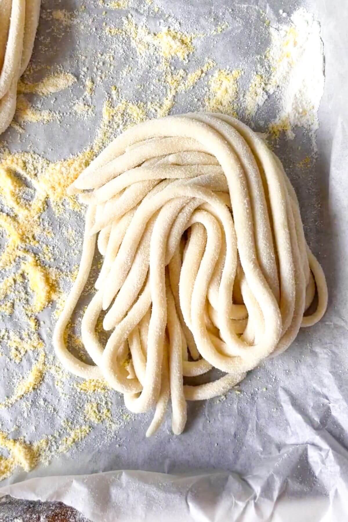 A nest of pici pasta on a lined baking tray.