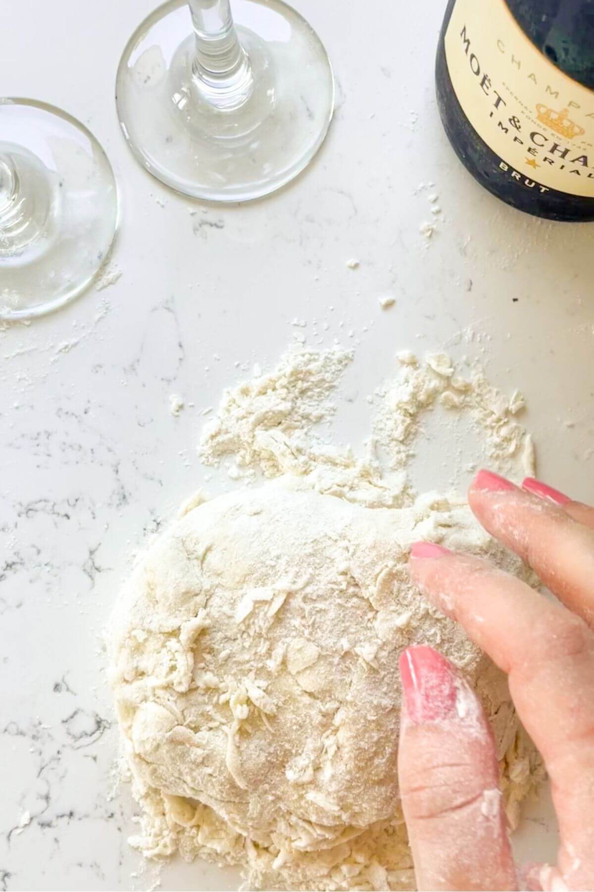 Hand kneading shaggy dough on the kitchen countertop.