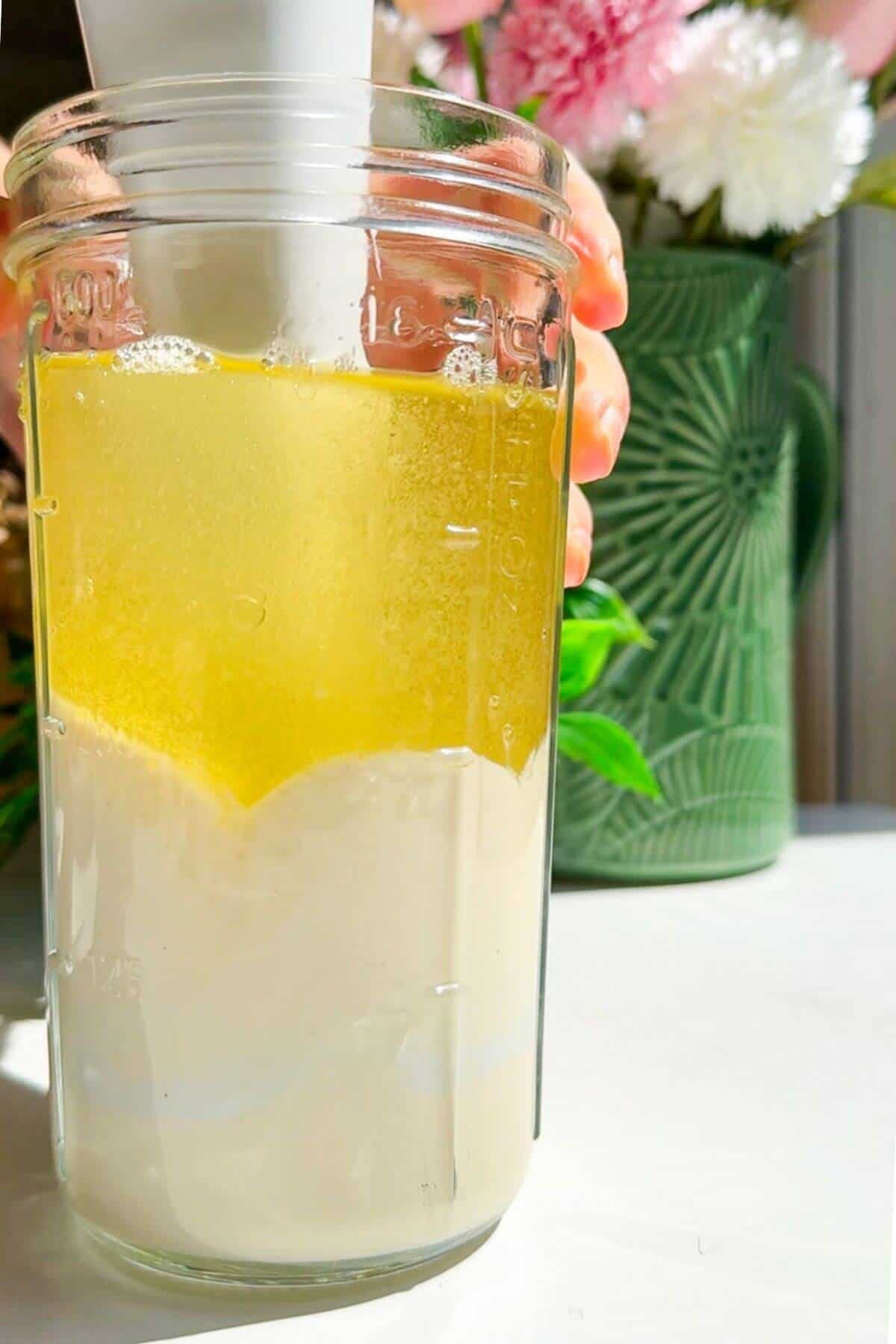 Immersion blender blending Kewpie mayo in a glass jar.