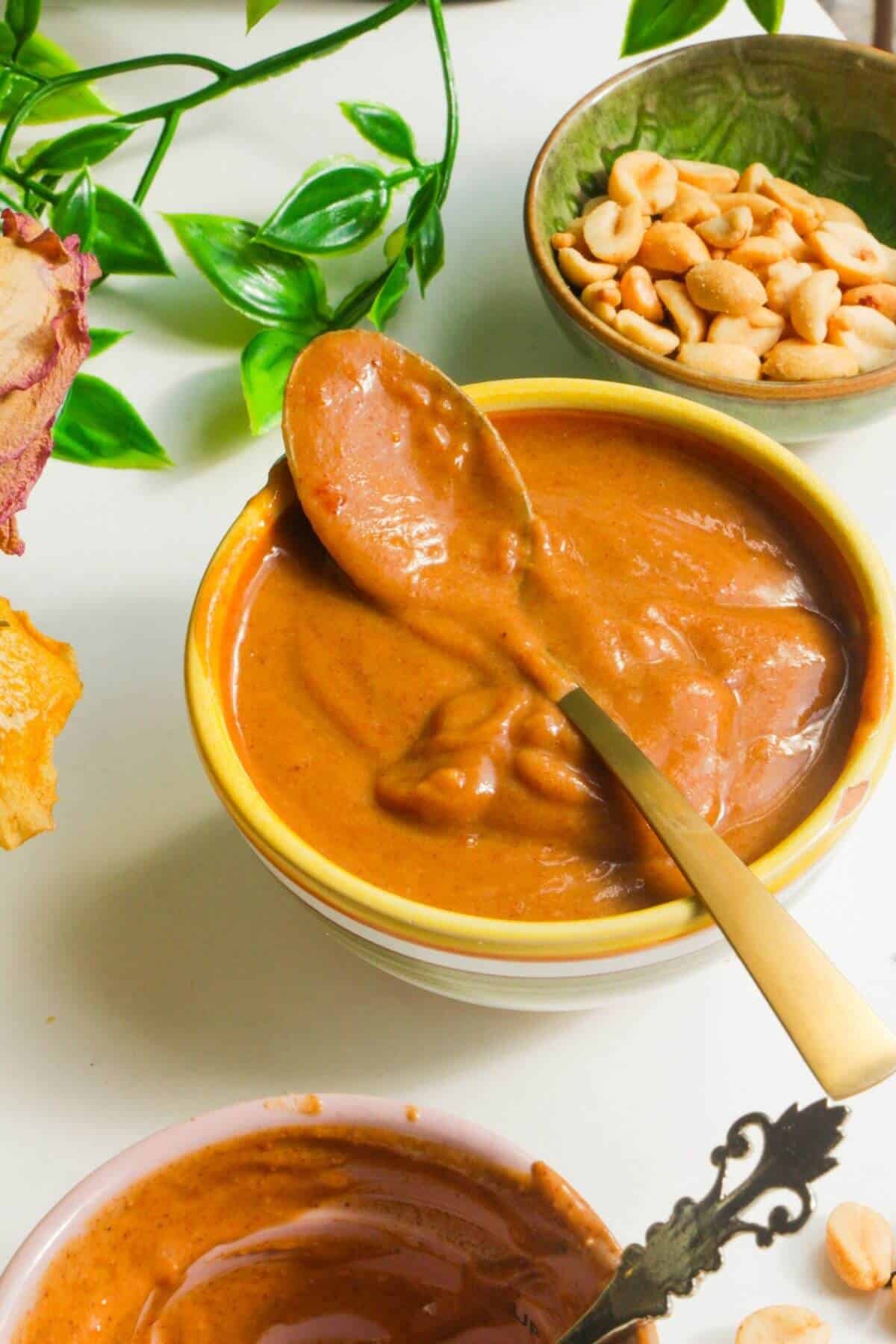 Peanut satay sauce in a small bowl with a spoon.