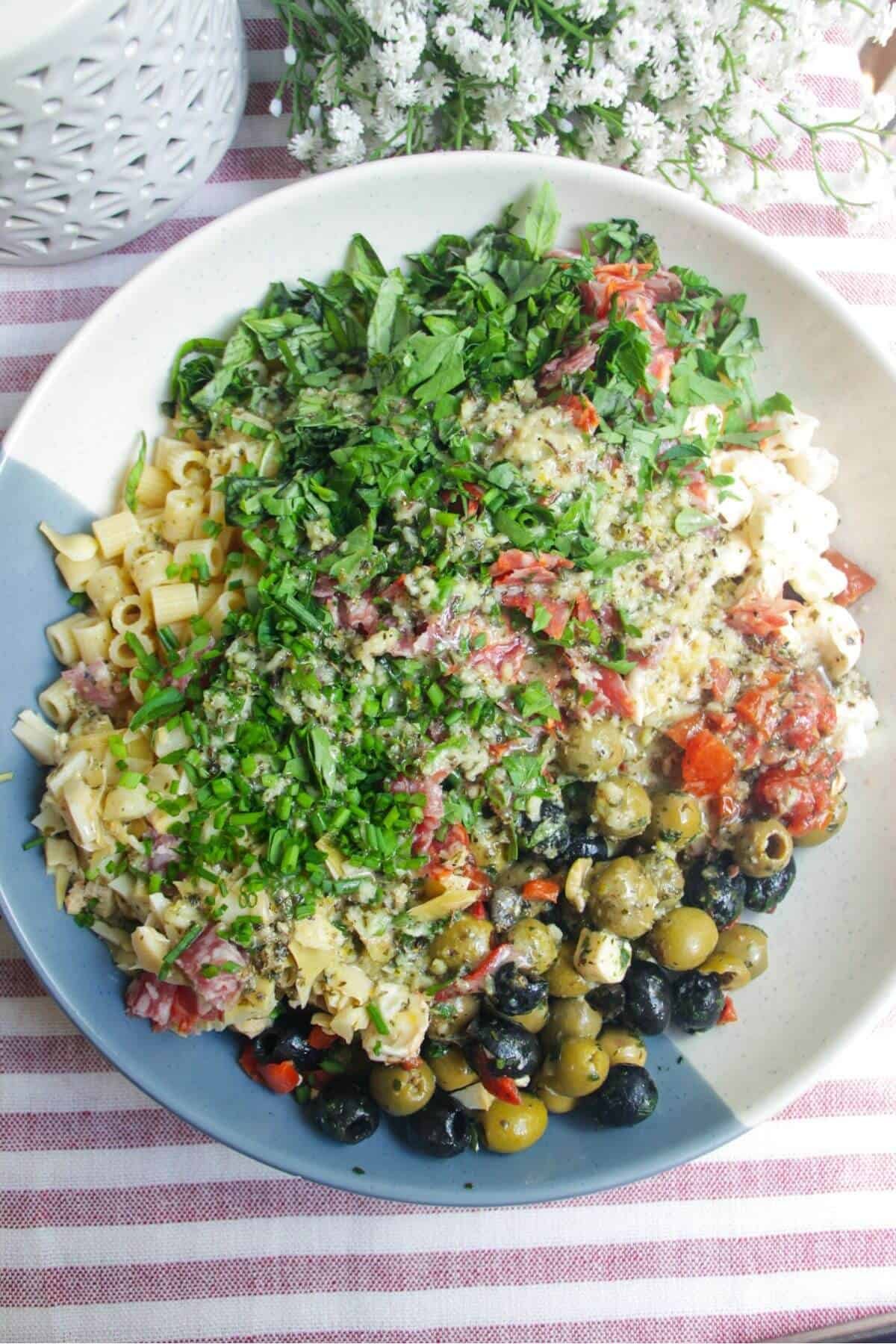 Dressing poured over pasta salad in large mixing bowl.