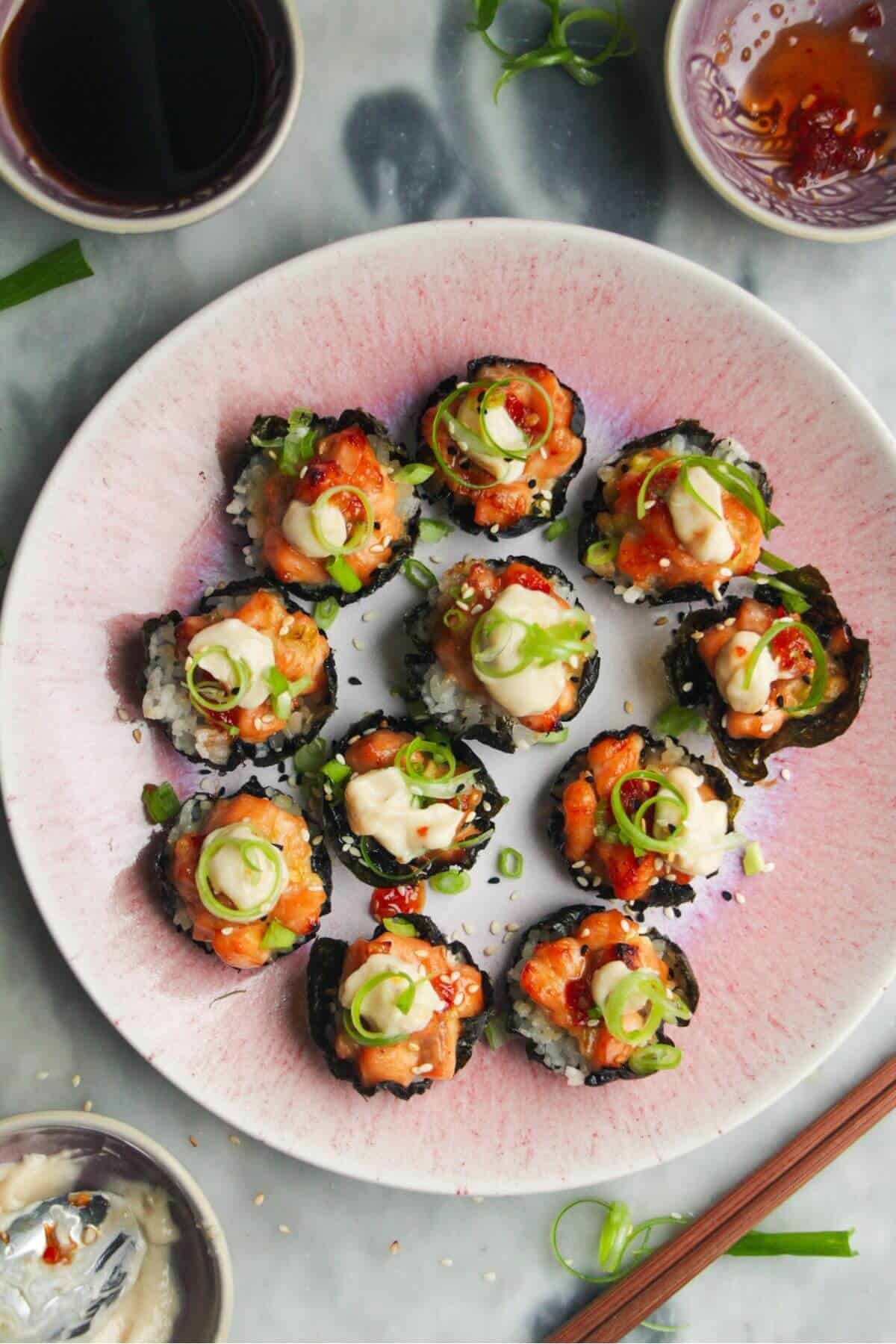 Salmon sushi cups on a pink plate, with aioli and sweet chilli on the side.