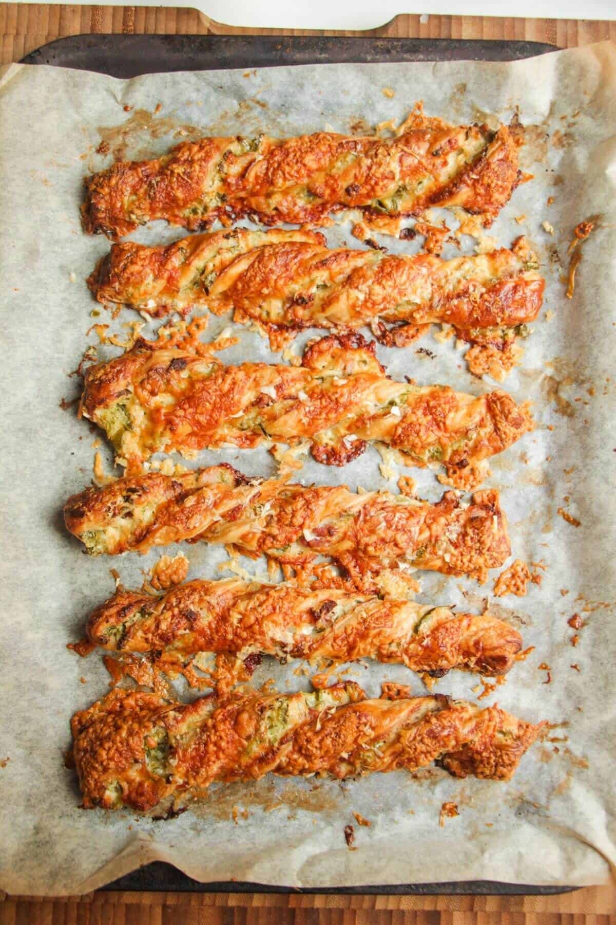 Cheesy jalapeno popper pastry straws baked on a lined tray.