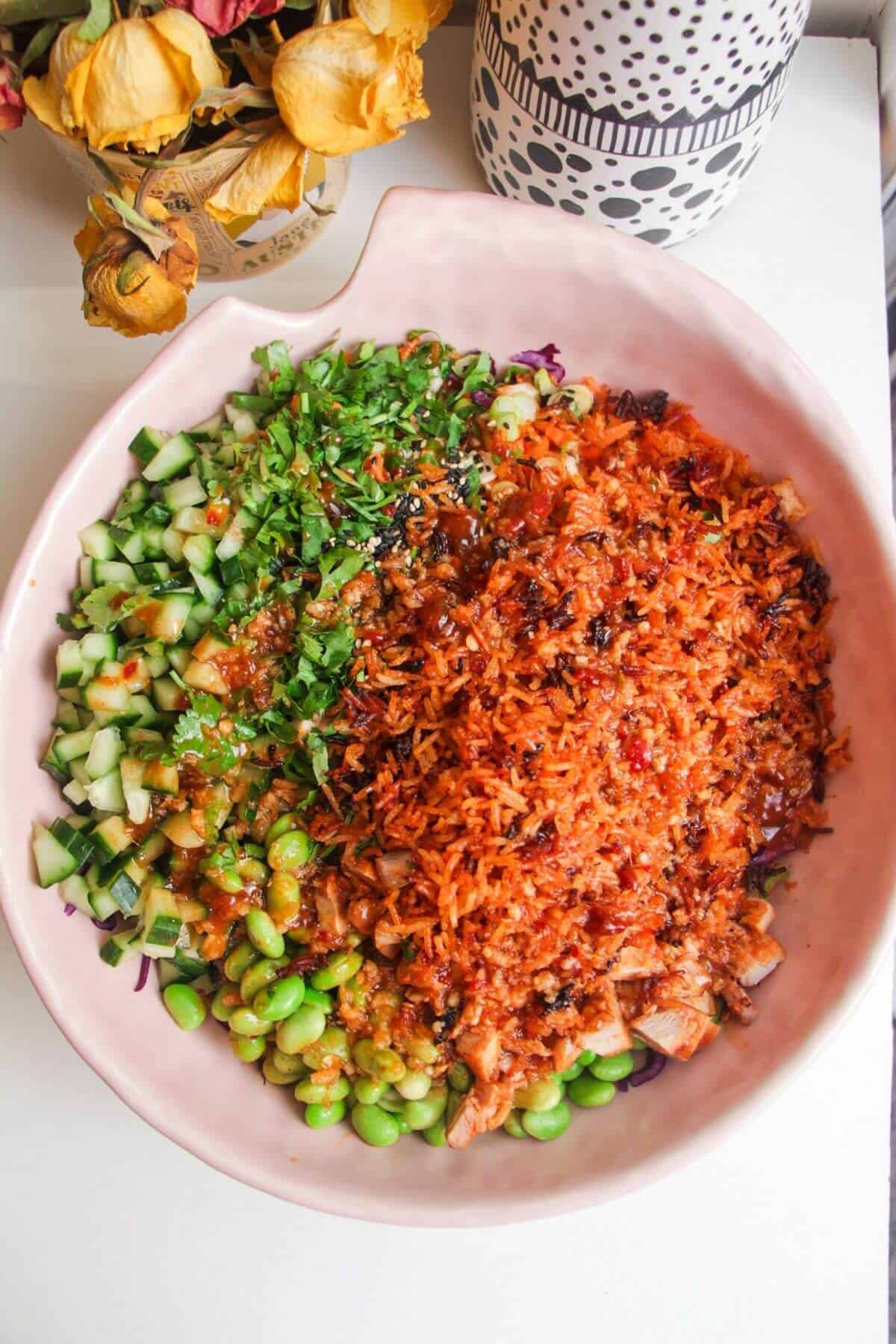 Crispy rice on top of chopped vegetables in a large pink bowl.