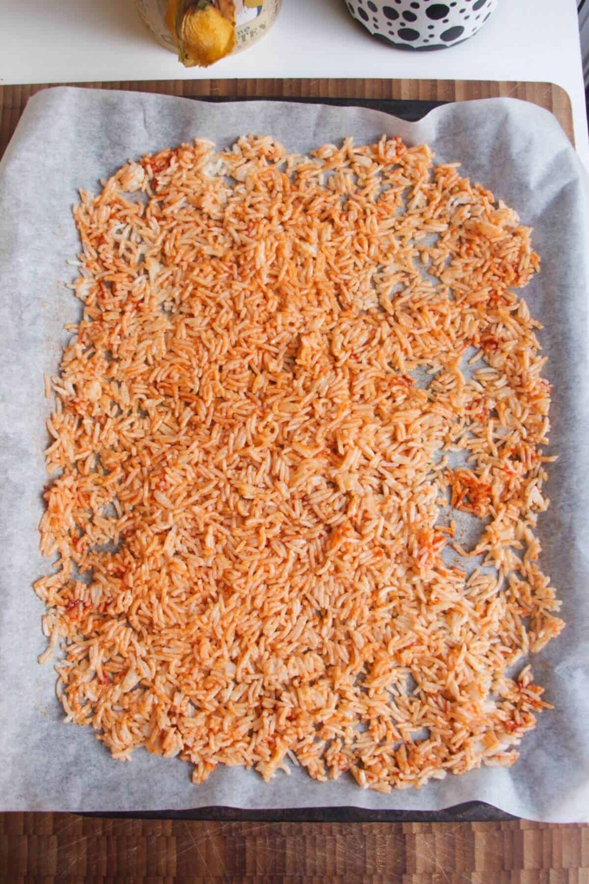 Rice mixed with gochujang paste and sesame oil on a lined tray.