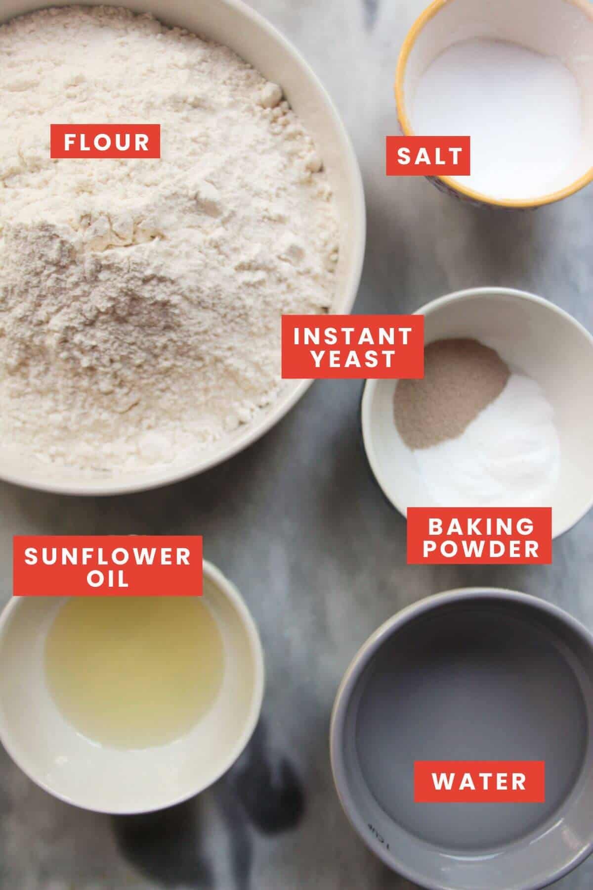 Ingredients for bao buns laid out on a grey marble background and labelled.