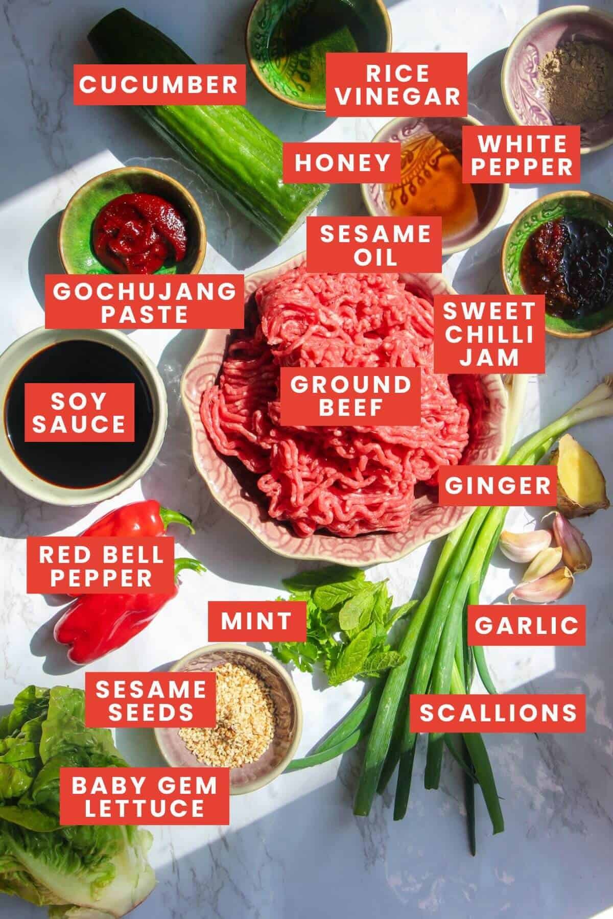 Ingredients for Korean beef lettuce wraps laid out on a whtie marble background and labelled.