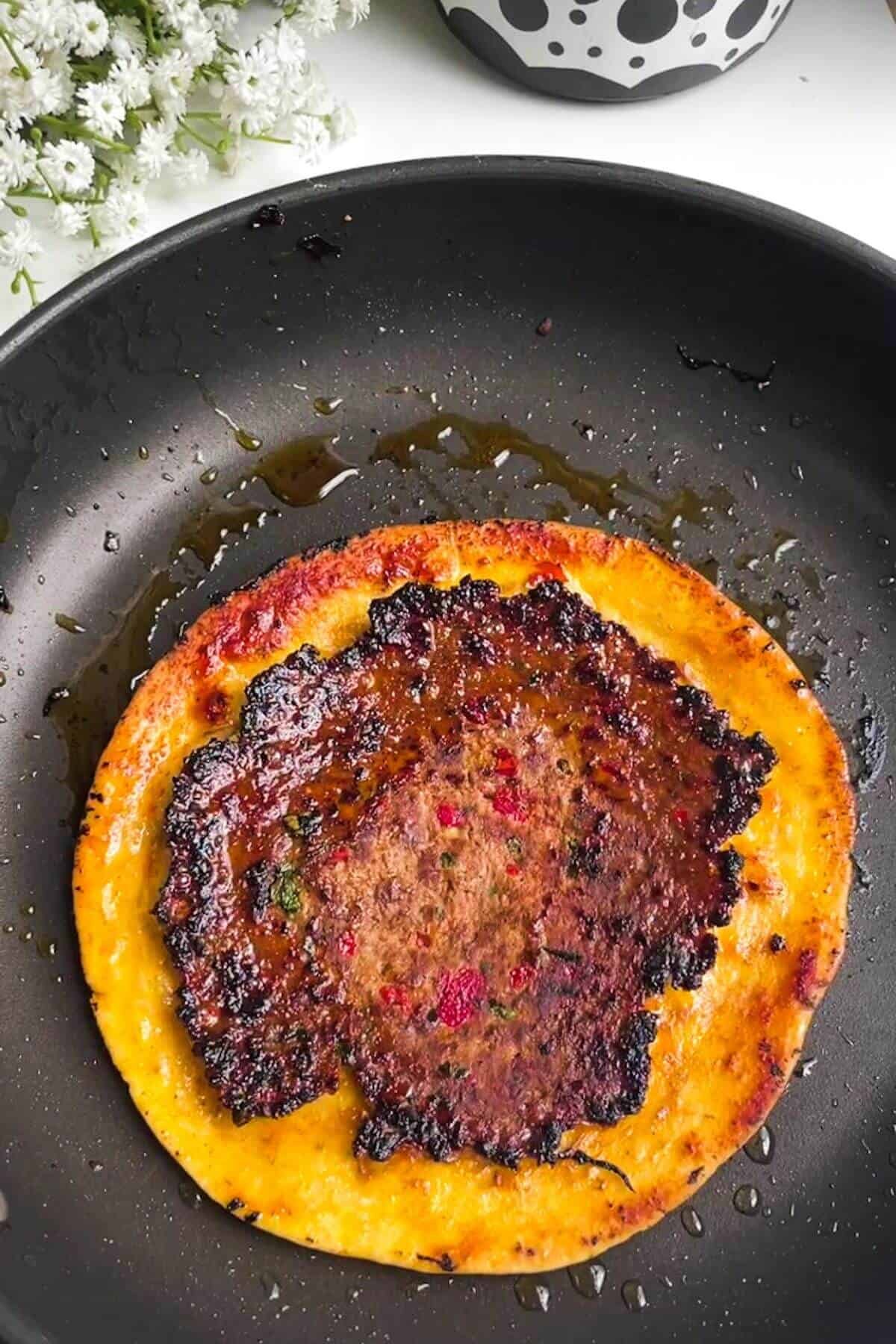 Lahmacun taco cooking in a small pan.