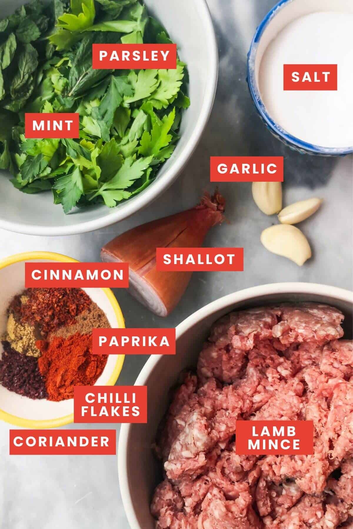 Ingredients for lamb kofta in little bowls on a grey marble background.