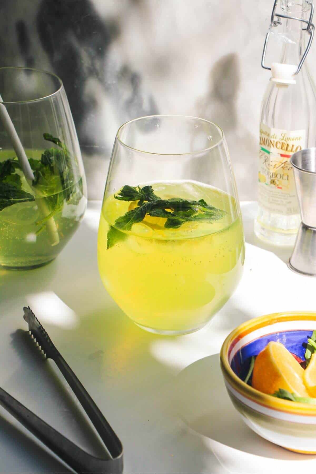 Limoncello spritz in a stemless wine glass with another spritz in the background.