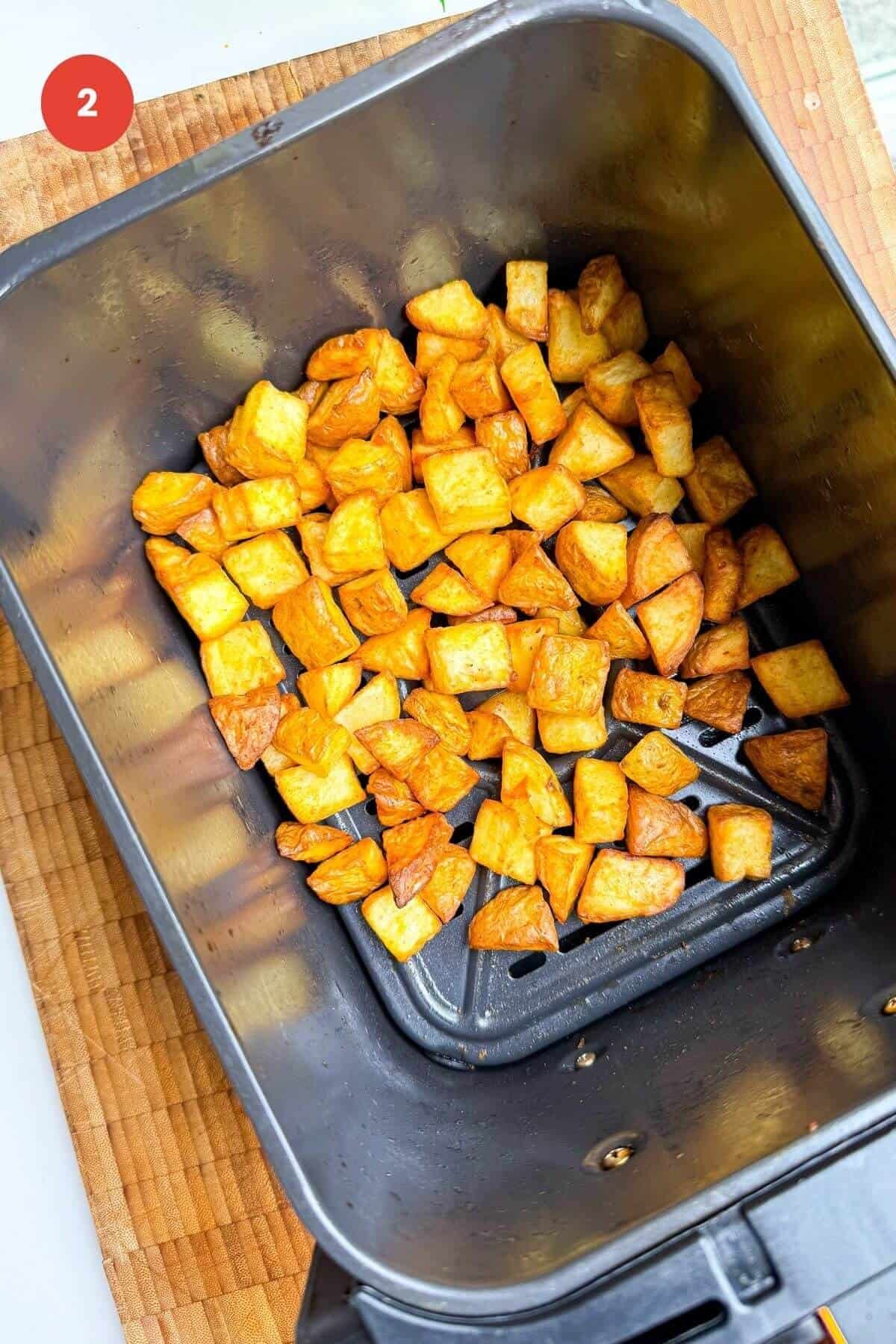 Air fried cubed potatoes in air fryer basket.