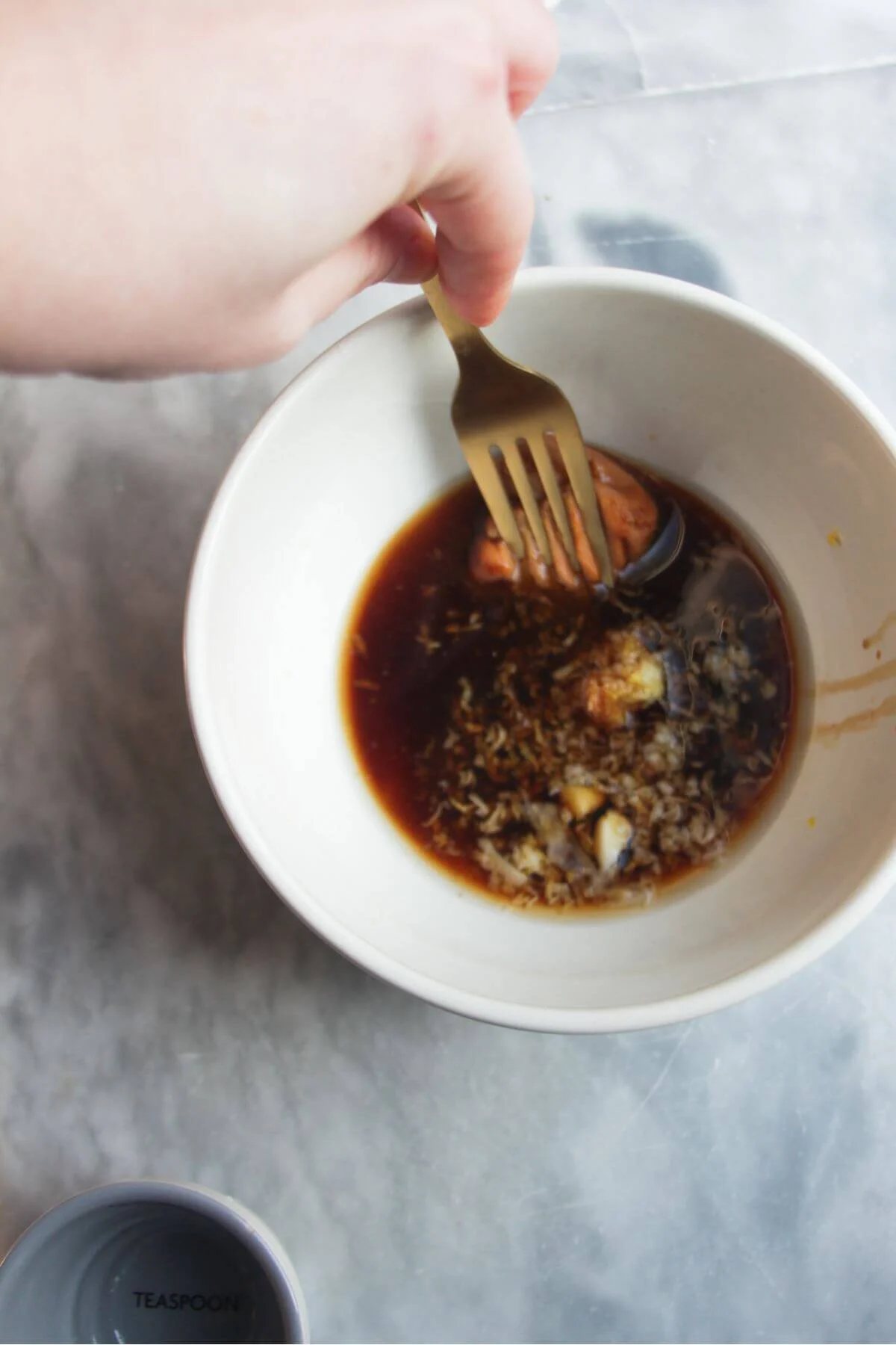 Gold fork mixing maple miso glaze in a small white bowl.