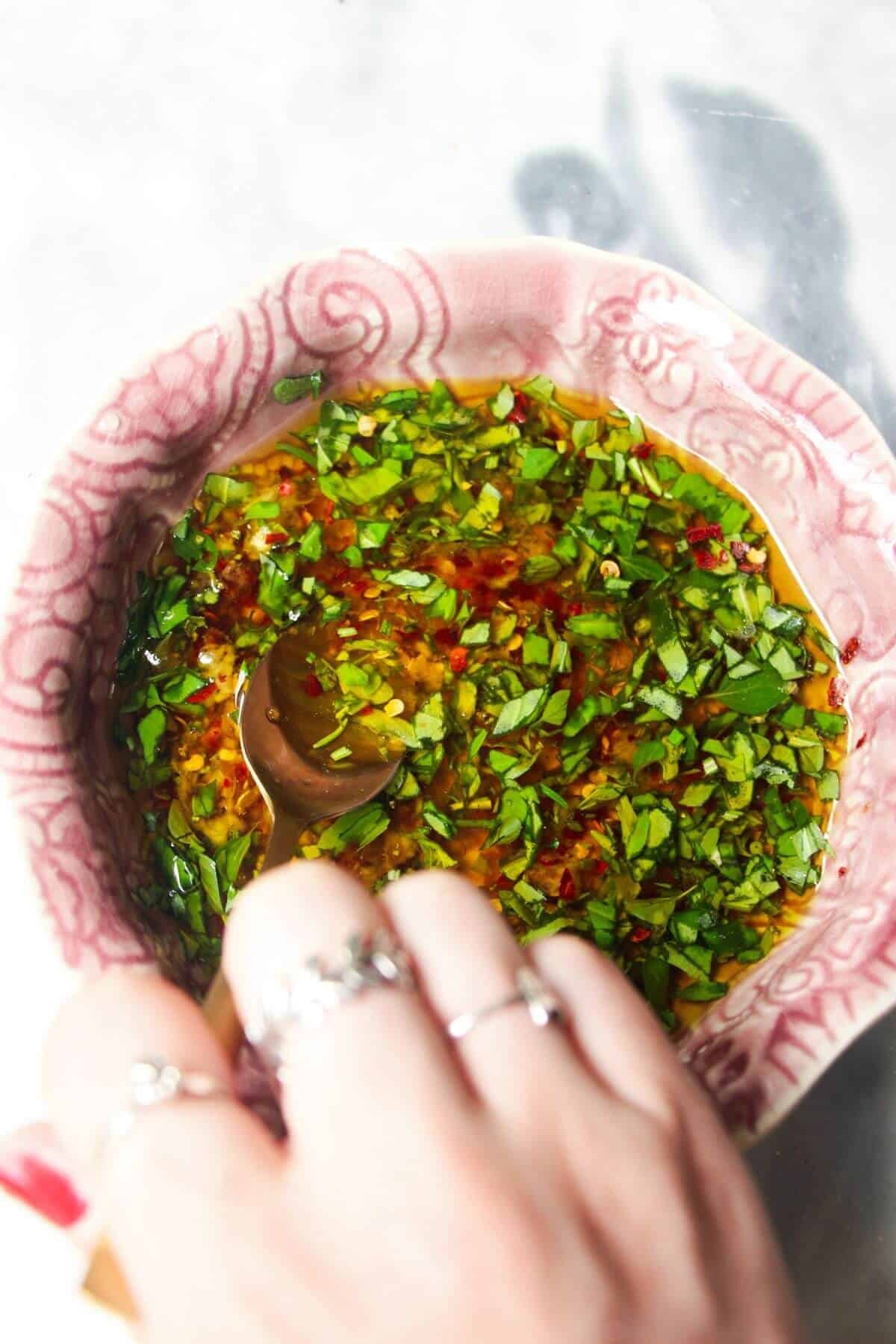 Mixing marinade ingredients in a small pink bowl with a gold spoon.