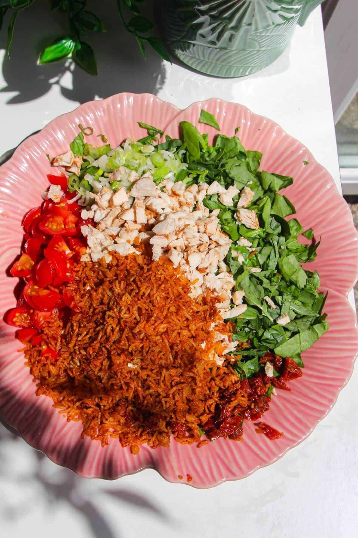 Ingredients for 'Marry Me' chicken crispy rice salad in a pink bowl.