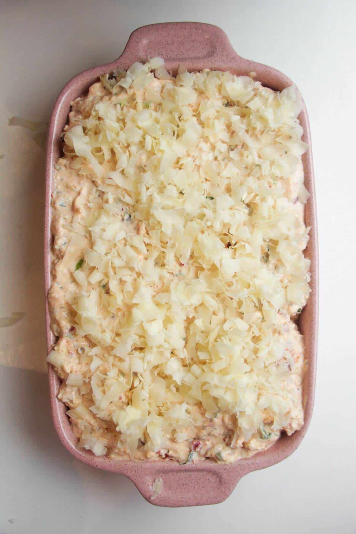 Marry Me chicken dip in a small oven dish, topped with grated cheese.