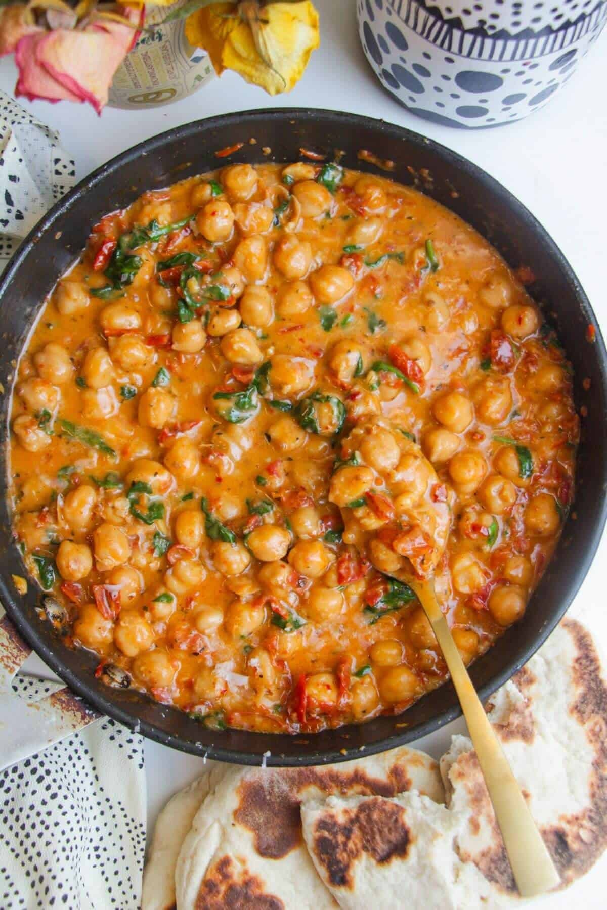'Marry Me' creamy chickpeas in a small pan with a large spoon in in.