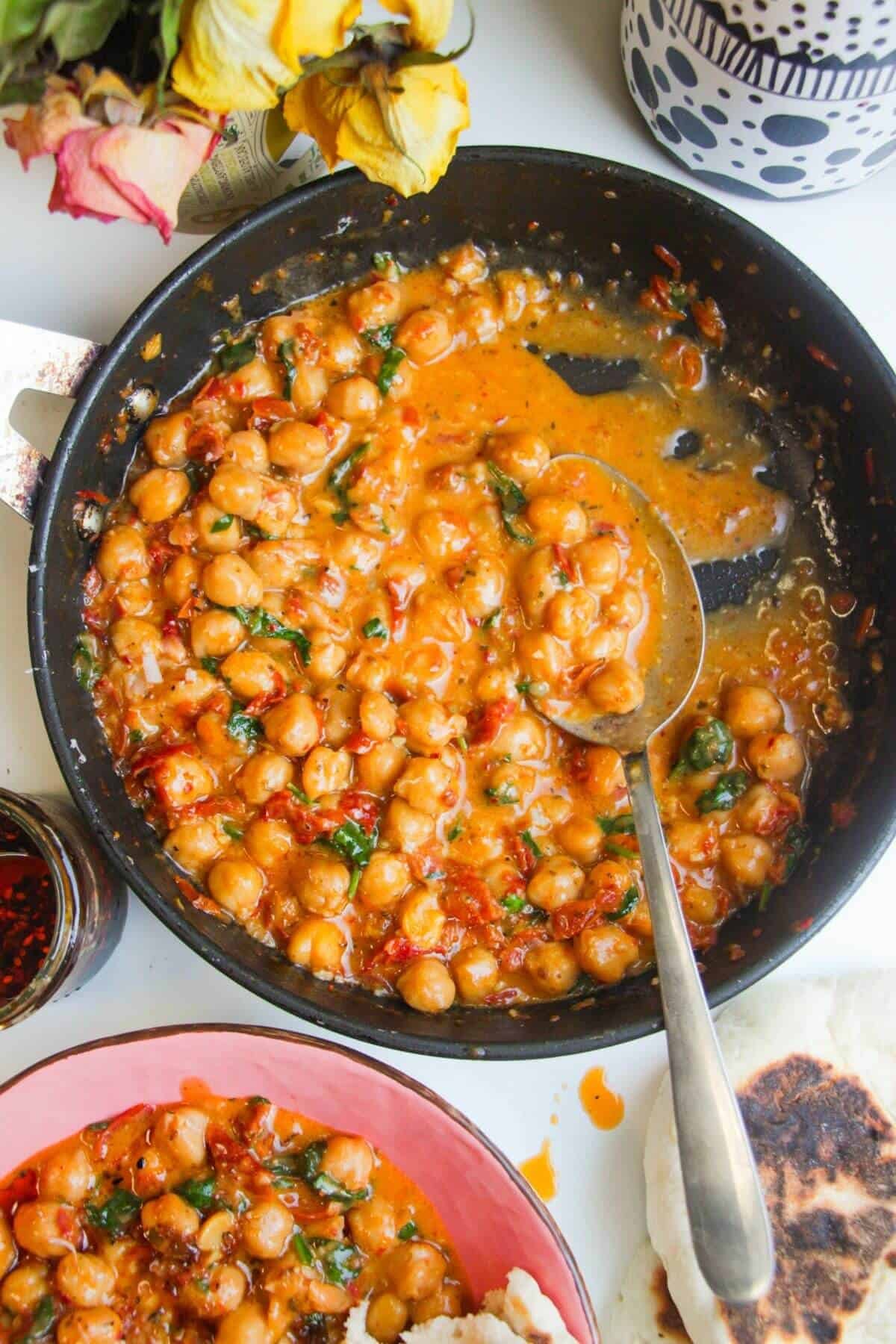 'Marry Me' creamy chickpeas in a small pan with a large spoon in in.