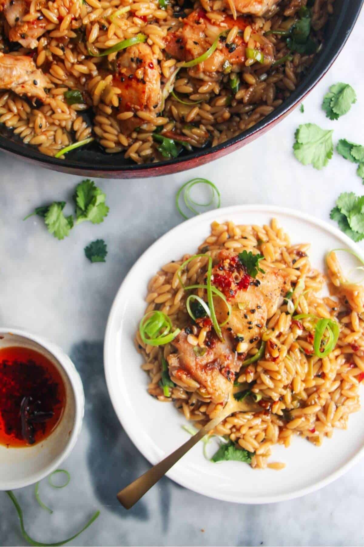 Ginger chicken orzo on a small white plate, with pot of more orzo in the background.