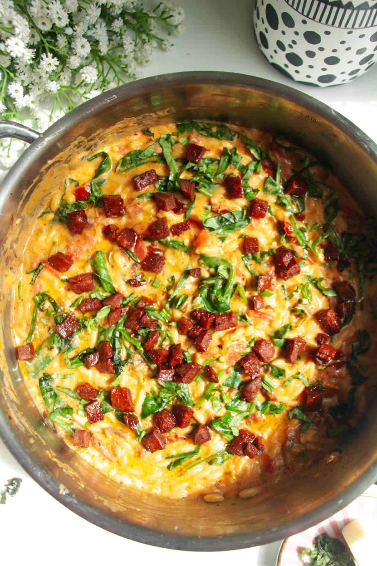 Crispy chorizo on top of creamy Marry Me orzo in a stainless steel pan.