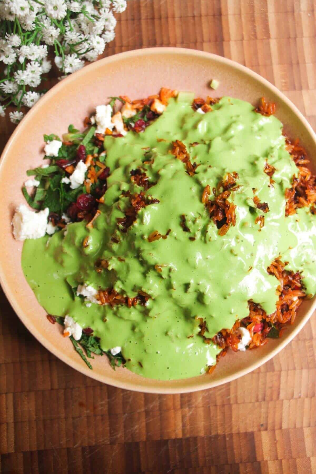 Green tahini sauce poured over Mediterranean rice salad.