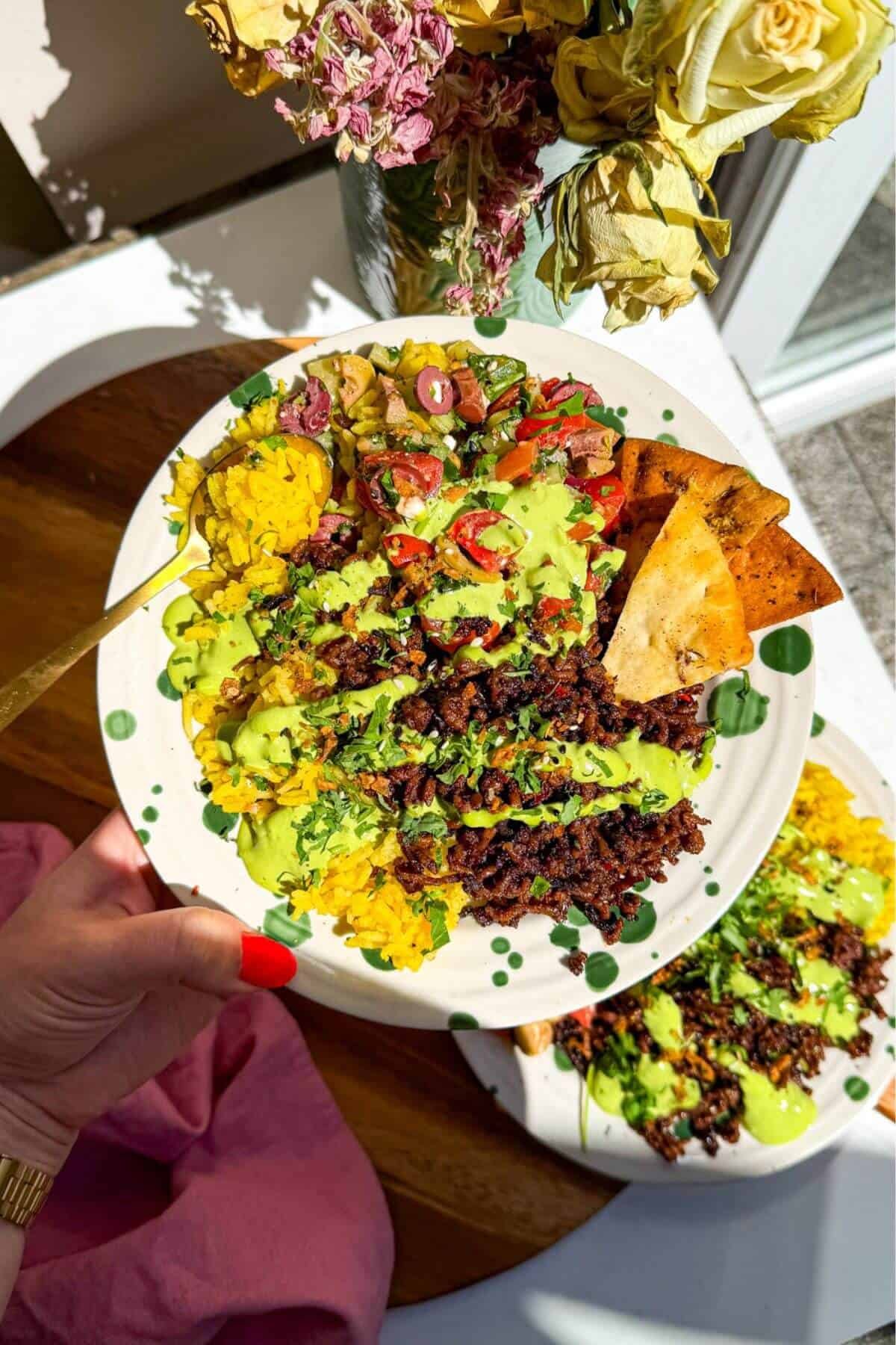 Hand holding up a Mediterranean beef rice bowl.