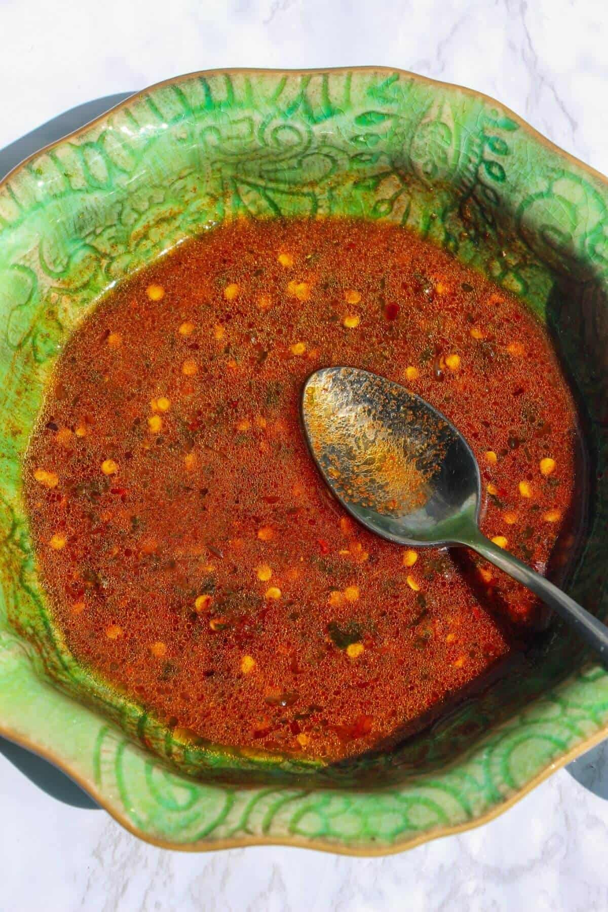Smoked dressing mixed with a silver spoon in a small green bowl.