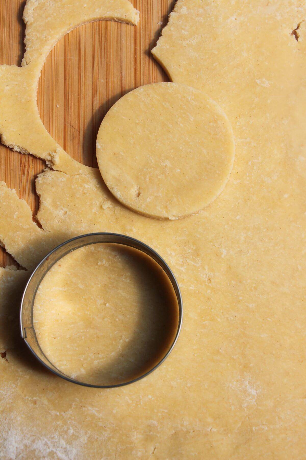 Cutting small circle of pastry out with metal cutter.